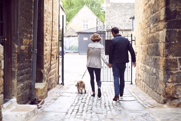 A couple walking a dog outside the Lygon Arms Hotel