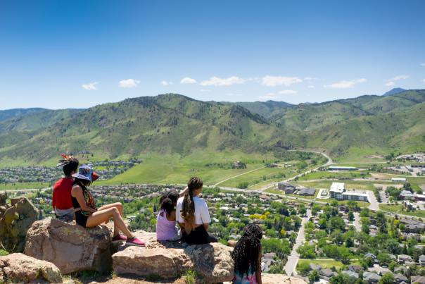 Family on a hike sitting down and looking off North Table Mountain over Golden in the Spring