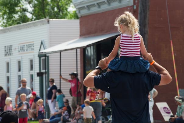 little girl on dad's shoulders during parade