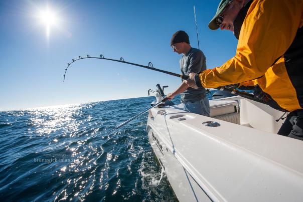 a man reeling in a big fish from a boat