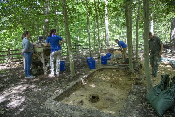 4-5 Archaeologists surrounding a dug out portion of land as they search for historical artifacts