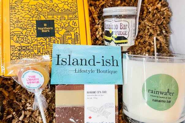 A box of goodies from Island-ish, includes a candle, soap, candy, and fragrances.