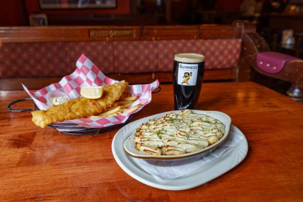 A breaded fish meal with a side of potatoes, and a dark beer