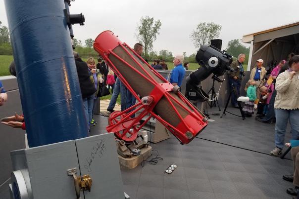A group of people at the Fort Wayne Astronomical Society stand with Star Quest Telescopes looking at the sky