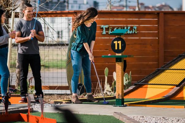 Three people playing putt-putt golf at a bar in San Marcos, TX
