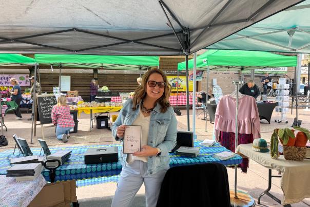 Author J.L. Hyde holding one of her books up at the Gladstone Farmers Market
