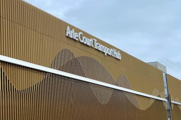 A gold or bronze building with Arle Court Transport Hub written in white on the top right.