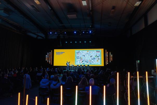 Dark event room with big presentation screen lit up and light displays