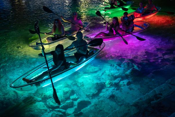 A group take a glow kayak tour on the San Marcos River