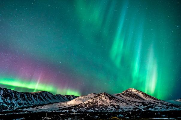 The Northern Lights create a kaleidoscope of color above snowy mountains in Alaska