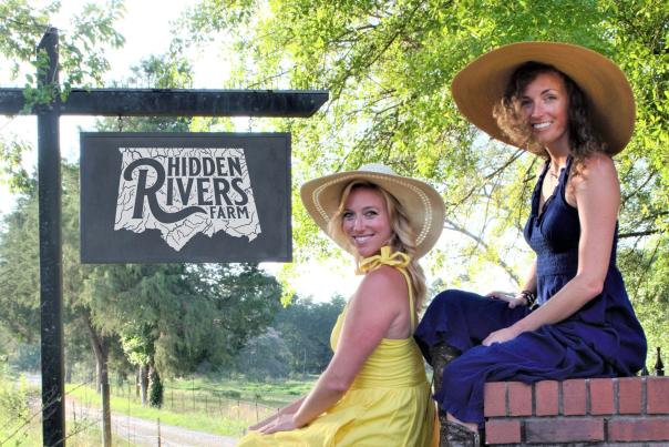 Sisters Abigail and Mary-Sidney Ritch pose in front of the Hidden Rivers Farm sign.