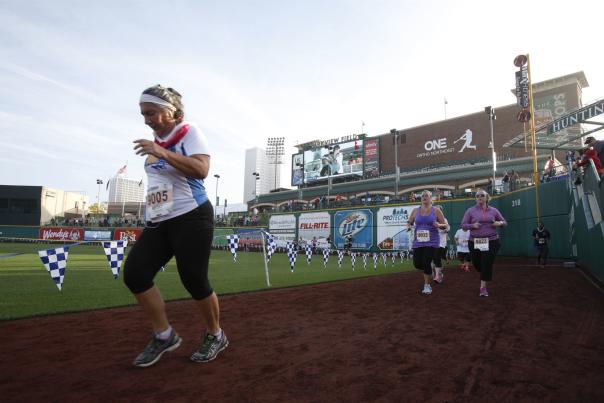 A woman running inside Parkview Field at the end of Fort4Fitness