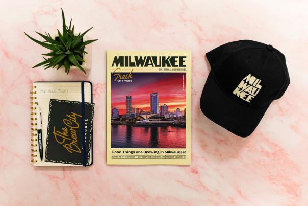 layflat display of a notebook, milwaukee visitor guide, and baseball cap