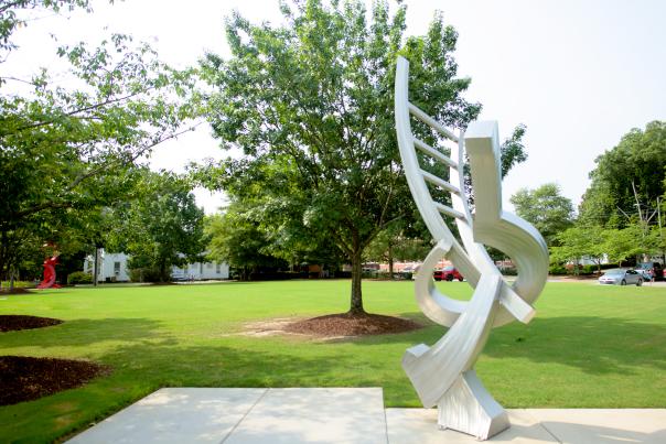 A silver geometric sculpture stands in a green park