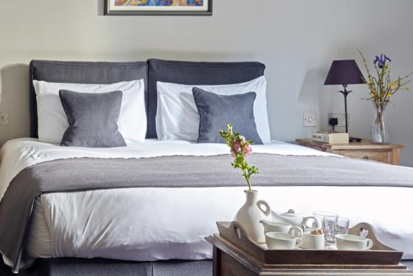 A sumptuous hotel bedroom at the Cotswold Grange, showing double bed and armchair