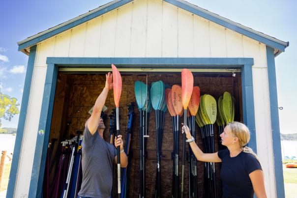 A white man and a white woman size up oars as they rent a kayak from Brittingham Boats