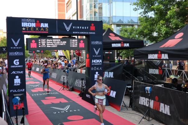 People running across finish line at Memorial Hermann IRONMAN Texas in The Woodlands, Texas