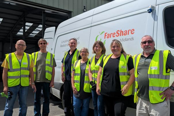 A group of people wearing high-vis vests stood next to a van that reads 'fareshare'
