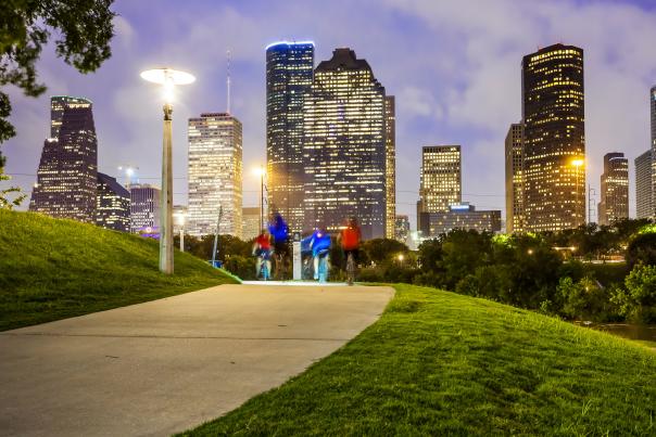 People biking through a park at night in downtown Houston, Texas.