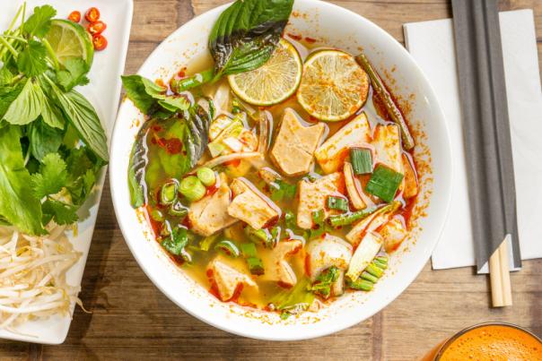 Two plates and a bowl full of vibrant food with chopsticks on the right hand side