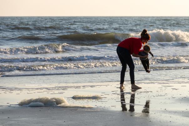 A mom playing with their child in the surf