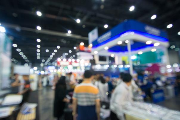 A group of people visiting booths at a tradeshow. The image is slightly blurred.