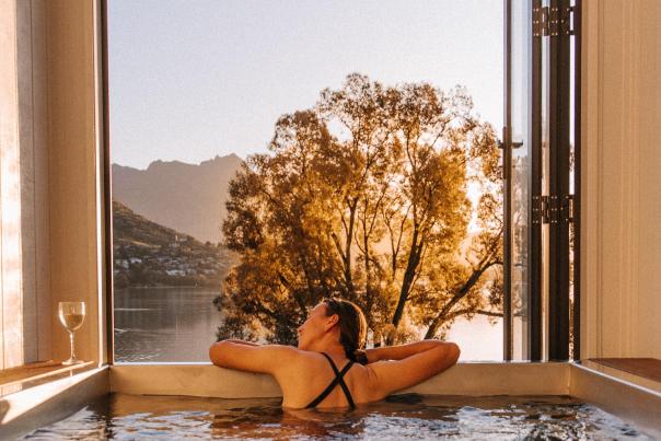 Person in hot tub with mountain and lake views in the background