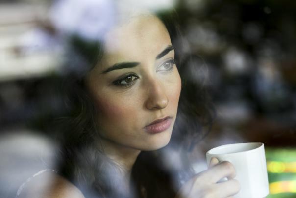 woman holding a coffee cup and staring out of a window