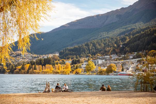 Peolple sitting at a beach in Autumn with town and mountain views