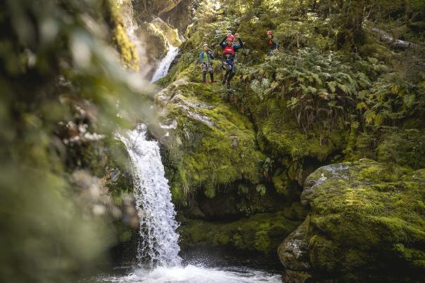 Person canyoning, jumping off a waterfall into a natural spring