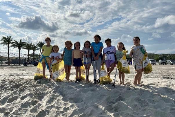 Girls who volunteered to clean the beach holding trash bags and grabbers.