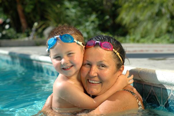 A grandmother and her grandson hugging in a swimming pool