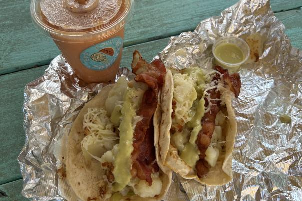 Two breakfast tacos in foil unwrapped with a pink smoothie from Veracruz All Natural.
