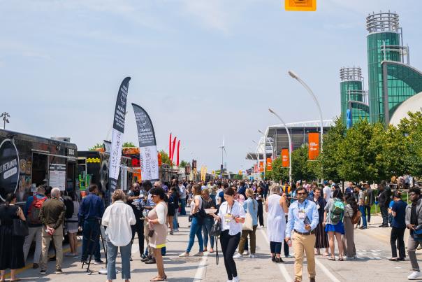 People walking outside Exhibition Place during Collision Conference in front of food trucks