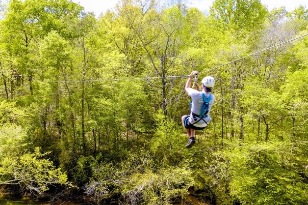Person with helmet ziplinging through the trees