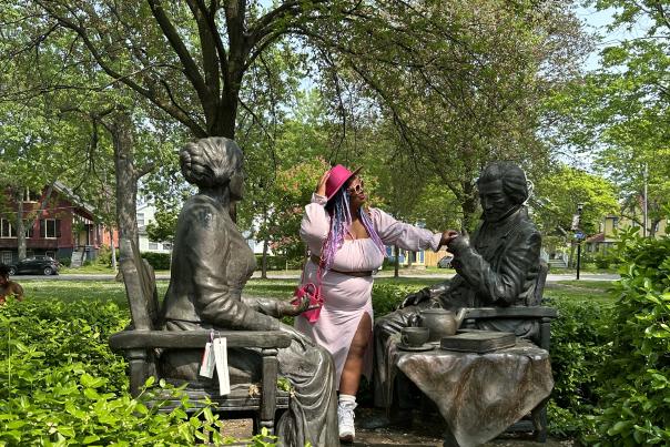 Let's Have Tea statue in Rochester, New York including Susan B. Anthony and Frederick Douglass with bushes and trees in the background