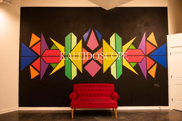 Kaleidoscope mural behind a red velvet couch