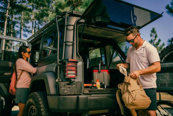 A couple getting ready to go biking, packing their packs from the back of their SUV.