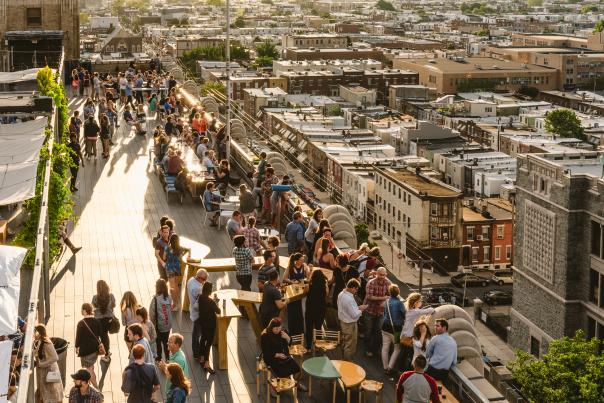 Aerial view of people mingling and enjoying themselves on a rooftop bar in Philadelphia in the summer