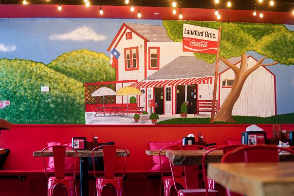 The interior of Lankford's evokes rustic charm with thick wooden tables, red metal chairs, and a hand-painted wall depicting what appears to be the original 1930s Lankford's grocery store.
