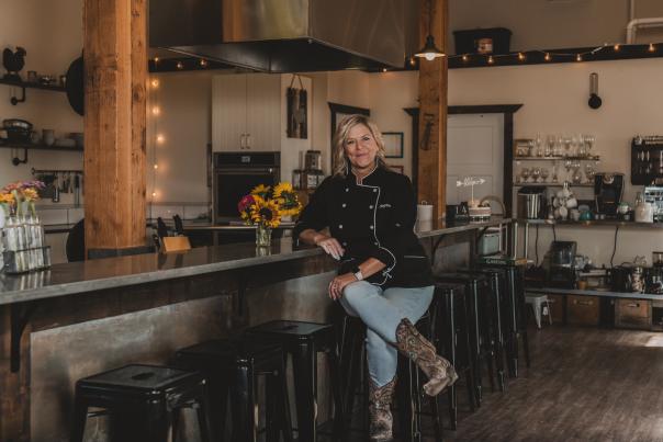 Woman chef sitting on stool at bar area in commercial kitchen