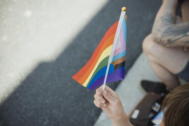 A person holding a small pride flag.