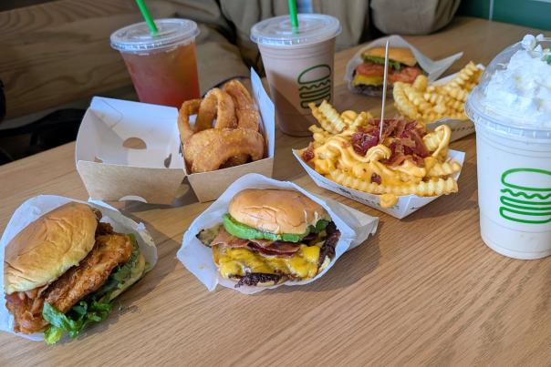 Shake Shack meal spread featuring burgers, crinkle-cut fries, and milkshakes on a table.