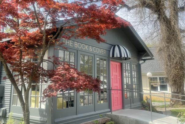 exterior photo of The Book & Cover bookstore with maple tree and hot pink door