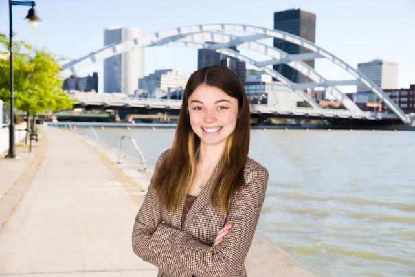 Headshot of Elisa Everett, Visitor Services & Accounting Specialist, in front of Genesee River and downtown Rochester, NY.