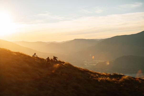 Three people biking on a mountain at sunset
