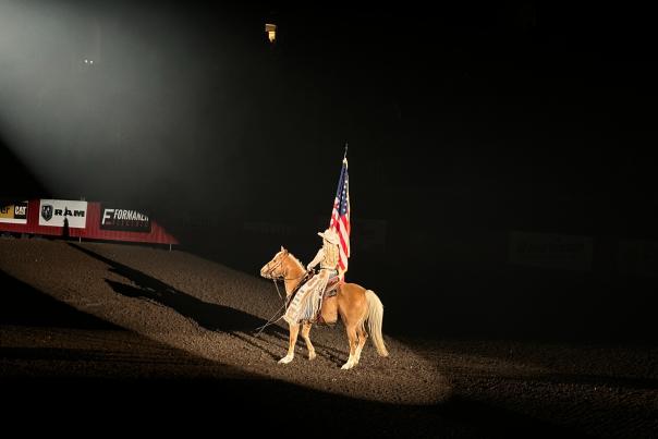 Cowgirl holding the American flag in the arena before the rodeo in rapid city, sd