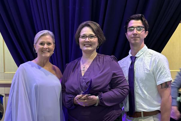 three people displaying an award