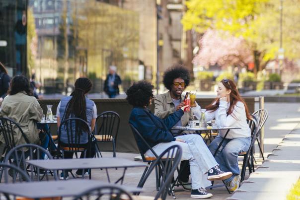 Group of friends sat outside restaurant in the sun in Manchester