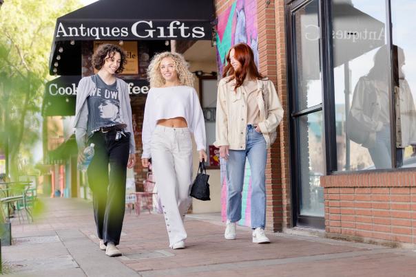 Three women walking downtown past antique and gift stores